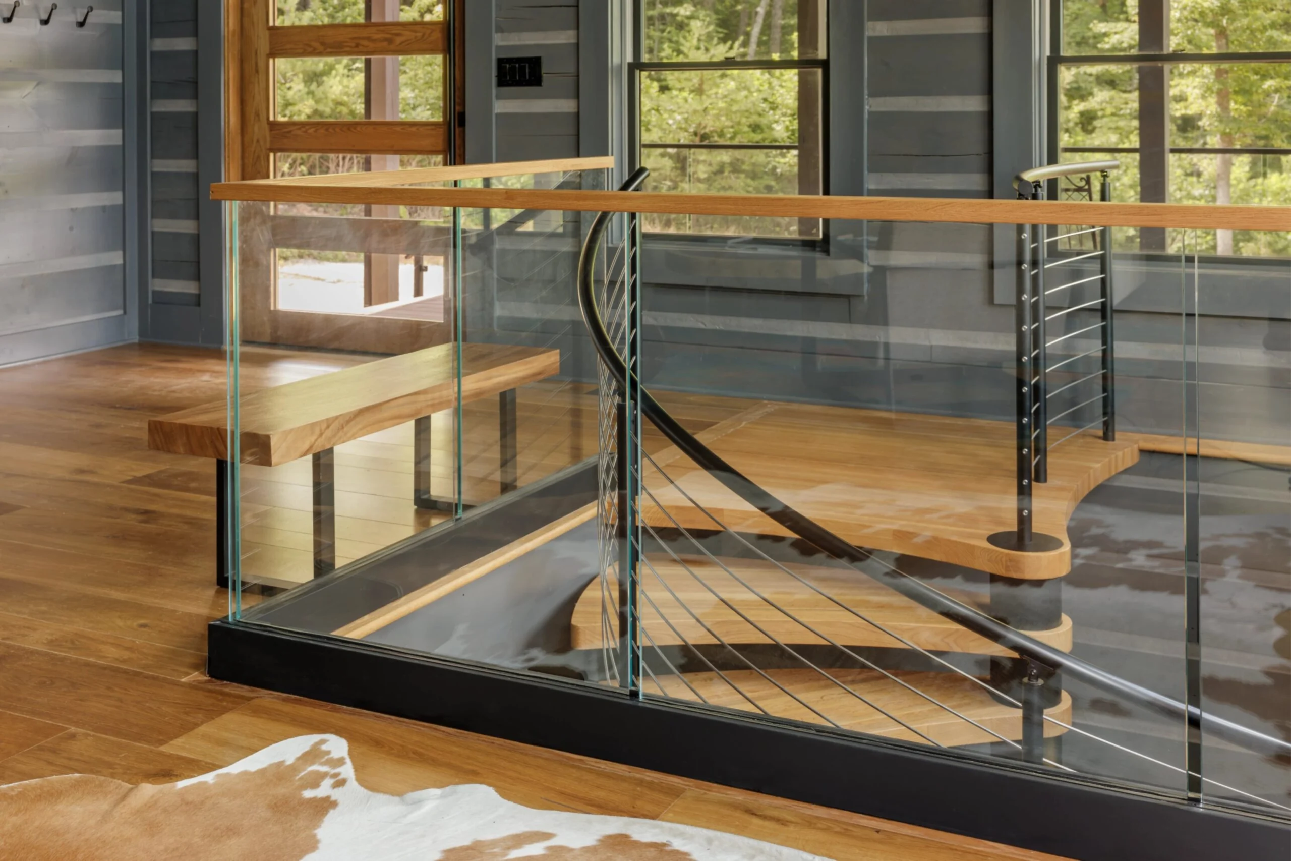 An interior FLIGHT Spiral connects to a Base Rail glass railing at the top of a landing.