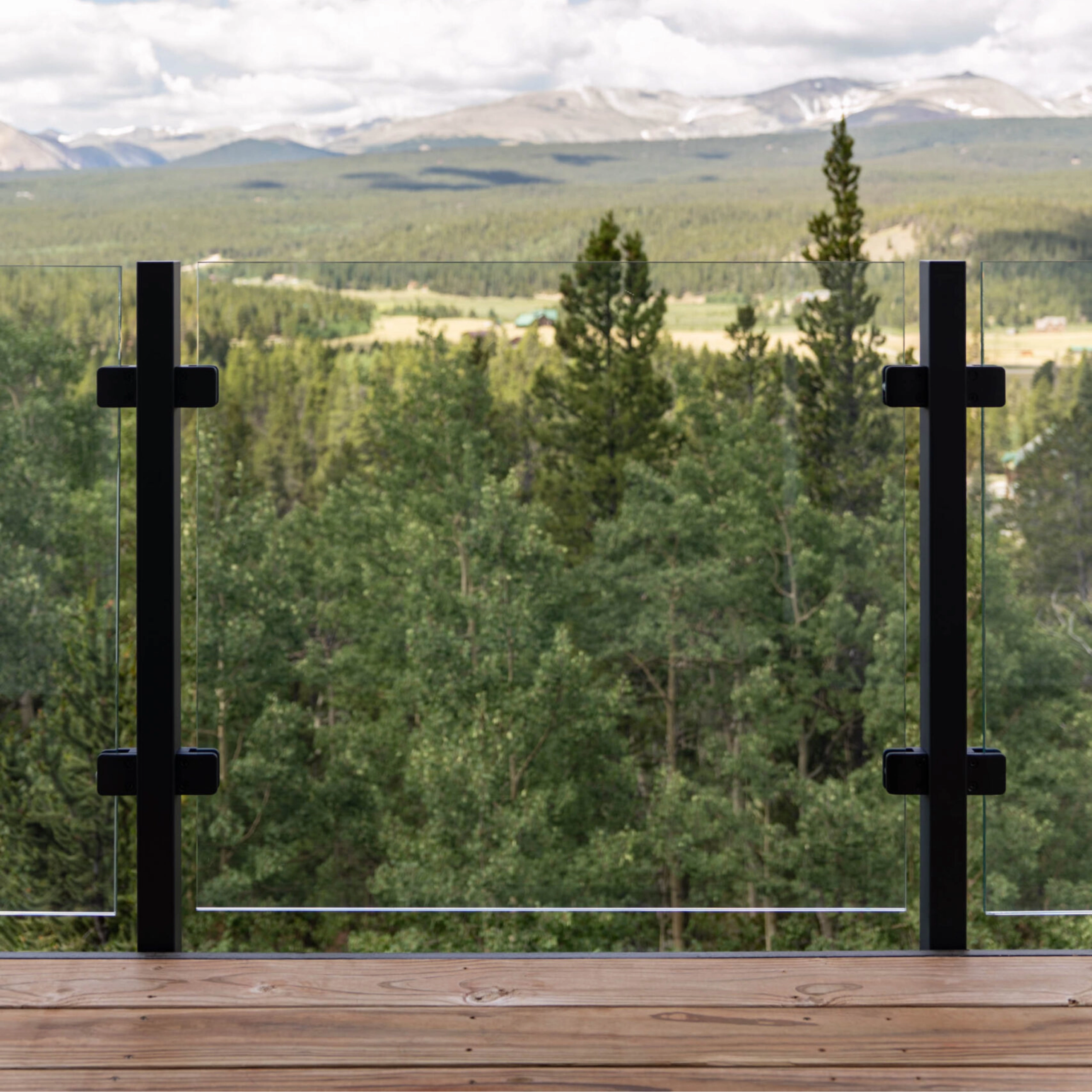 Exterior glass railing on a balcony overlooking a valley and mountain range.