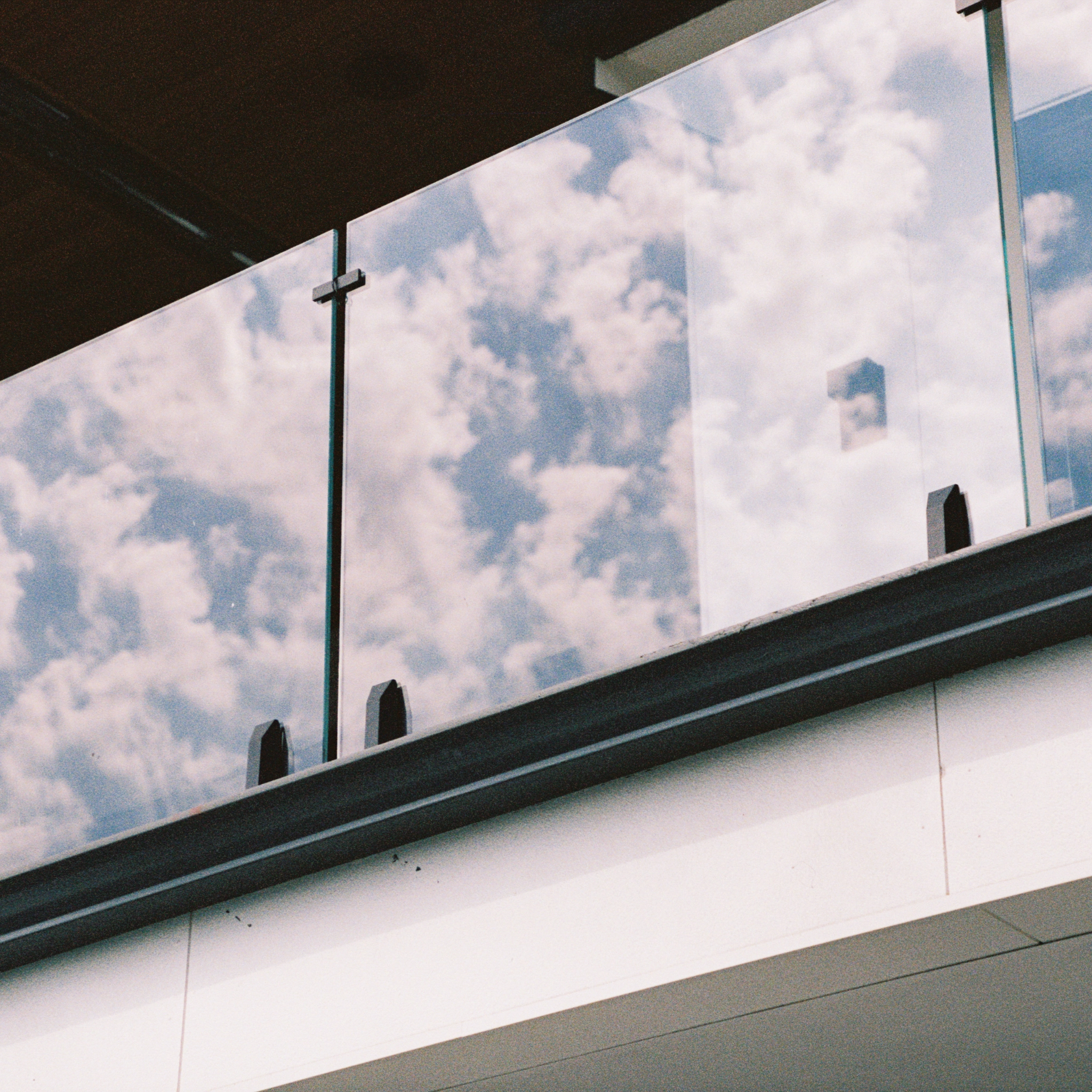 Viewrail glass panels with Talon spigots, reflecting a cloudy sky.
