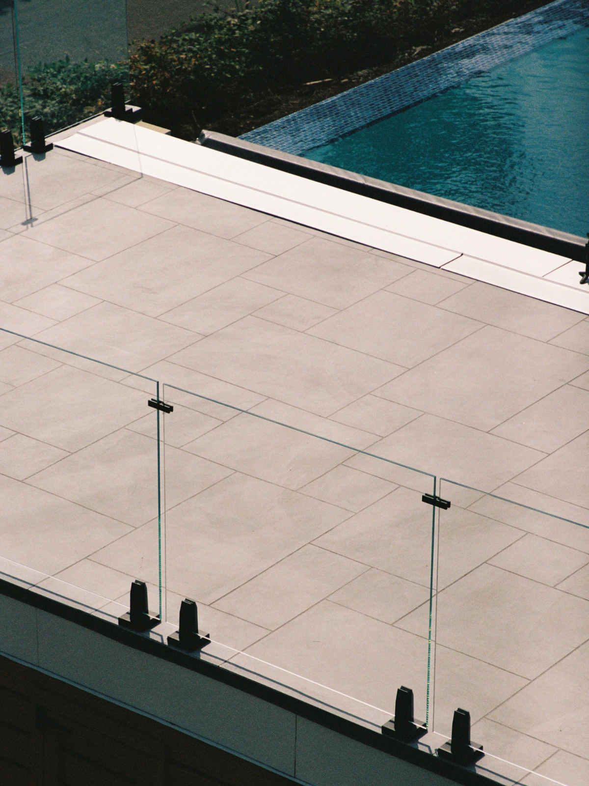 An exterior glass railing system with Talon Spigots shown near a pool.