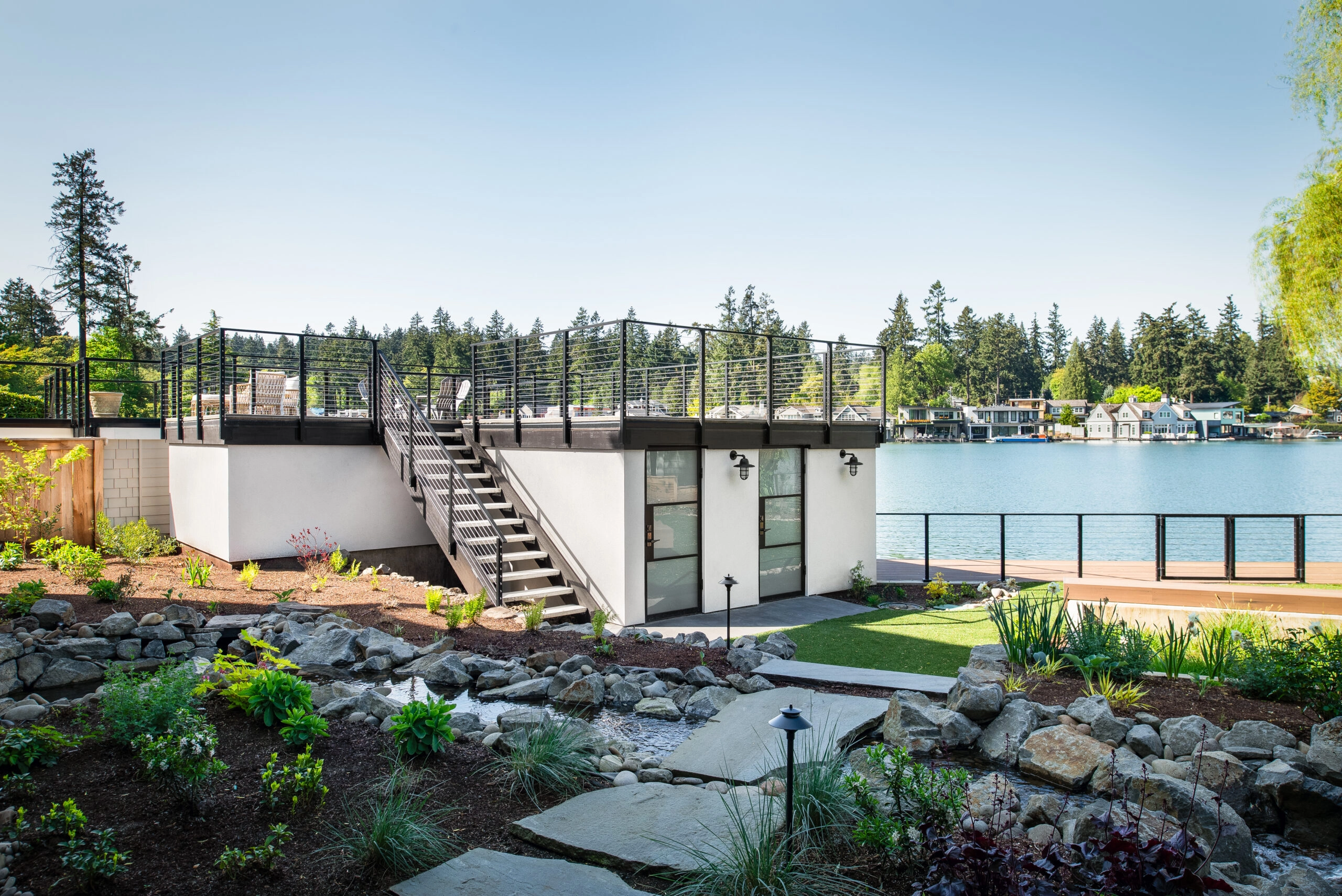 Side mount signature cable railing shown on a large deck and stair overlooking a lake.